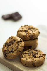 Pile of chocolate chip cookies on wooden board and white background 