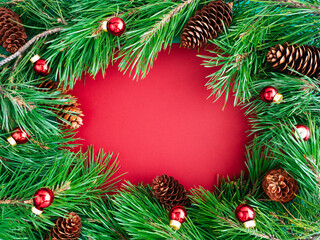 Fototapeta na wymiar Creative layout of Christmas tree branches and cones on a red background, top view, copy space, flat layout. The concept of New year and Christmas. Bright new year background or greeting card