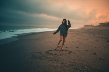 San valentino, ragazza fa un cuore sulla spiaggia