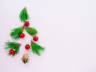 Christmas tree branches and red toys on a pink background, flatly, top view.