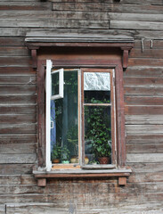 window in an old wooden house with flowers in the village
