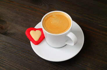 Cup of Hot Coffee with a Heart Shaped Cookie on Dark Brown Wooden Background for Valentine's Day Concept