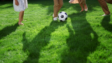 Closeup of parents and kids feet playing with soccer ball in green park