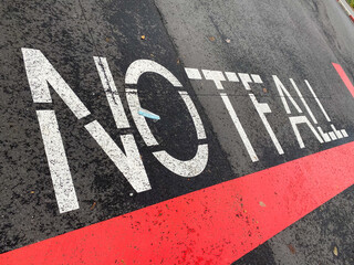 View on isolated german word Notfall (english meaning: emergency) with red line paint on asphalt at...