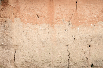 Orange old plaster wall with crack. The wall is faded and damaged.