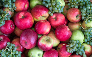 green grape with red apple on old wooden table.