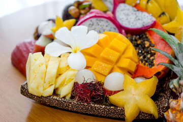Juicy ripe tropical Thai fruits on a wooden dish.