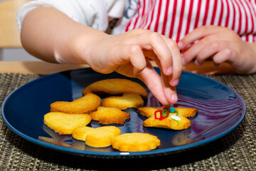 Close up view of kid’s hands decorating homemade cookies for holidays. A child decorates cookies with edible colorful sugar pearls.