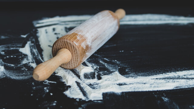 Wałek do ciasta z mąką na ciemnym czarnym tle do pieczenia
