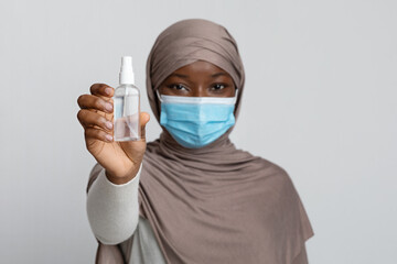 Bottle Of Disinfectant Spray In Hands Of Black Muslim Woman In Mask