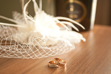 wedding rings symbol attributes lie on a table with hat or veil, glasses and bottles of champagne.