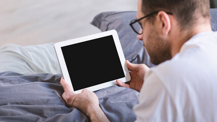 Man Using Digital Tablet With Empty Screen Lying In Bed