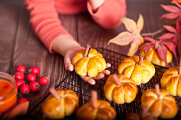 Pumpkin buns on the baking rack. Autumn concept.Baby girl take a one bun.