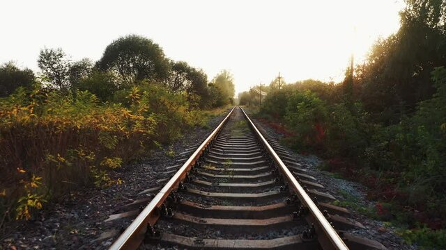 Railroad track at sunset in the countryside. Low flight of a drone over the railway.