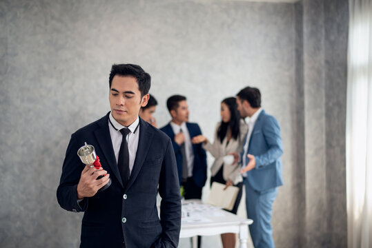 Businessman happy pride with win cup and business team jealous behind