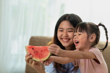 Happy Asian child enjoy eating a ripe juicy watermelon with her older sister