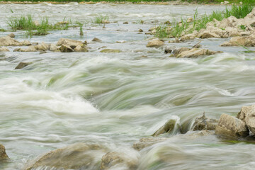 The flow of the river in the summer forest. Stones washed by water. Reflection on the water. water movement for a long exposure.