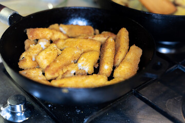 fried fish sticks-fingers in a pan close-up