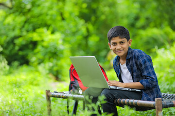 Technology concept : Cute indian little school boy using laptop