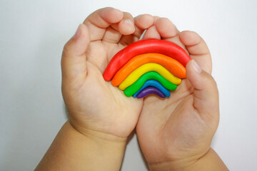 child hands with colorful plasticine. Rainbow in a child's hand.