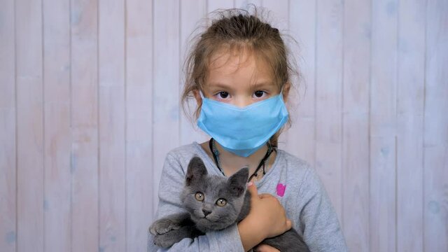 Child in medical mask with cat in hands during coronavirus pandemic. Careful patient care concept. Homeschooling during epidemic. Infection prevention and control IPC concept. Trust doctors concept