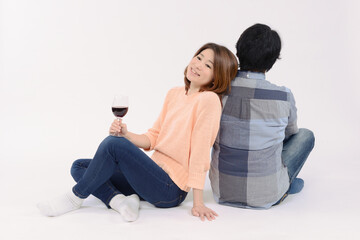 男性の背中に寄りかかりワインを飲む女性