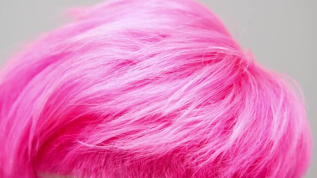 Young beautiful girl with a short haircut and pink hair. A homosexual lesbian model poses on a white background in the studio.