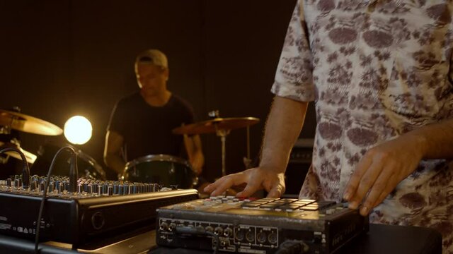 Music production studio. Beatmaking. Hispanic man recording new beats and caucasian man playing drums. Talented and creative persons record their ideas.