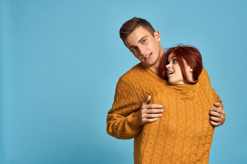 couple in love in yellow sweater posing against blue background cropped view Copy Space