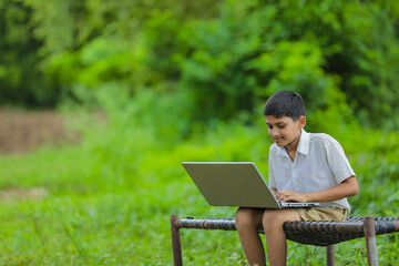 Technology concept : Cute indian little school boy using laptop