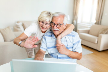 Happy old family couple talking with grand children using laptop , surprised excited senior woman looking at computer waving and smiling.