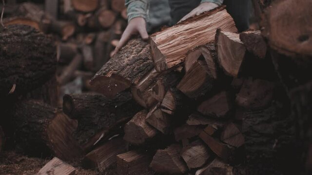 Man in denim stacks split wood on backyard