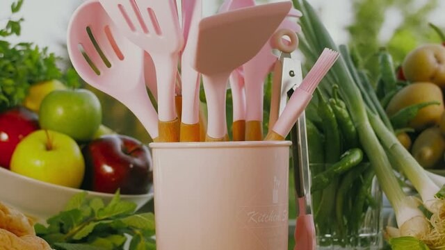 Sehr sch&ouml;nes K&uuml;chenbesteck dreht sich in einem Eimer im Hintergrund liegt frisches Obst