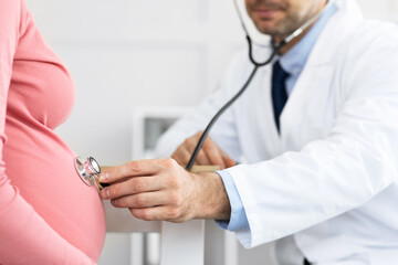 Mature experienced doctor examining young pregnant woman