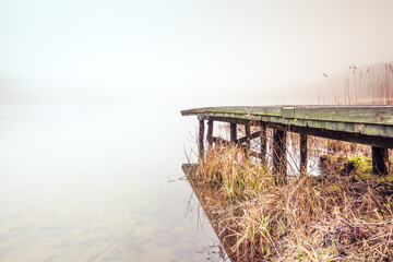 Obraz premium Misty lake in the middle of the forest and old wooden bridge