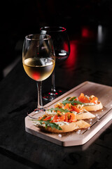 Set of snacks and glasses of wine. Bruschetta with cheese and salmon on a wooden board, served with red wine.