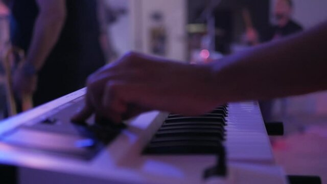 At the concert, the musician plays the synthesizer. male hands playing electric piano on concert stage, close up