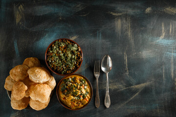 Delicious indian food curry in brown dish with bengali puff flatbread luchi and dal Indian food on wooden table top view with copy space