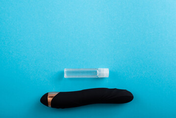 Top view of a black dildo and a bottle of lubricant on a blue background