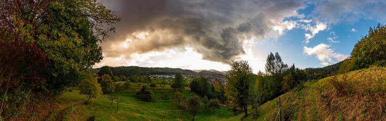 a beautiful panorama over green fields and dark clouds in the sky in the beautiful black forest in...