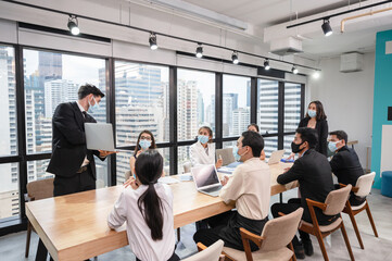 Caucasian businessman presentation of business plan on laptop at conference table, Group of business people wearing face mask meeting in modern office