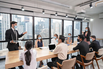 Caucasian businessman presentation of business plan on laptop at conference table, Group of business people wearing face mask meeting in modern office