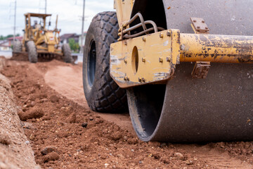 Fototapeta premium Close up Yellow vibratory soil and Motor Grader Civil compactor working on road construction site, Yellow vibratory soil compactor in road construction site