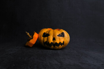big orange ripe pumpkin with painted scary face, halloween celebration, black background, place for text