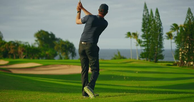 May playing golf on beautiful golf course at sunset, swinging and hitting golf ball in slow motion