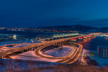 Fototapeta na wymiar A new road bridge over the Yenisei. connecting two parts of the city, next to the railway, illuminated by bright lights