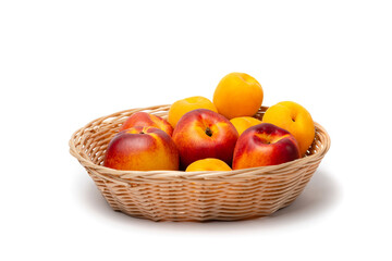 nectarine, peach and plums in a wicker basket on a white background