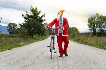 Santa Claus riding his bike on the street.