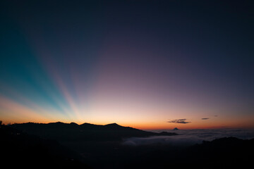 View of a colorful sunrise, where you can see a layer of clouds and some rays of sun