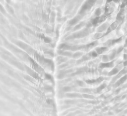 Fototapeta na wymiar White transparent liquid or water texture background.Photo of water waves shadow. Subtle texture of light-shadow pattern of sunlight reflection from rippled water surface. Beautiful natural wallpaper.